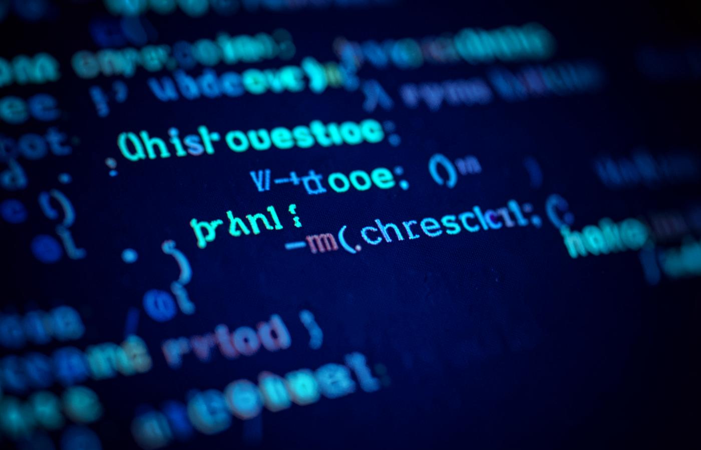 Macro photograph of program code rendered in cyan and blue on a dark screen
